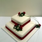 2 tier square stacked wedding cake with deep red rose sugar flower spray