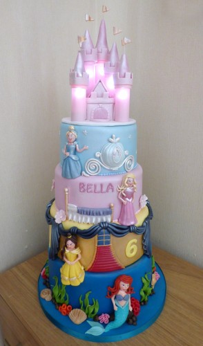 4 tier disney princesses birthday cake with an illuminated castle