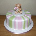 simple striped birthday cake with bear carrying a bouquet of roses