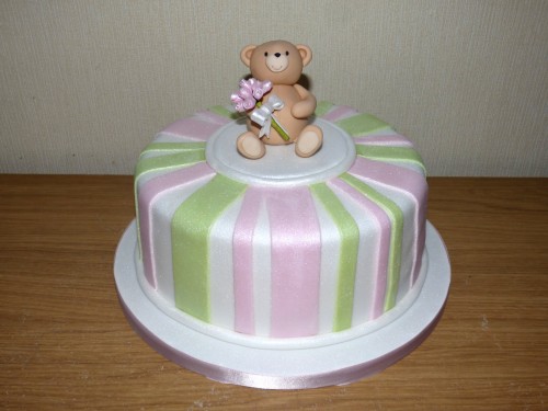 simple striped birthday cake with bear carrying a bouquet of roses