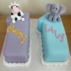 twins 11th birthday cake with cow and elephants and cupcakes
